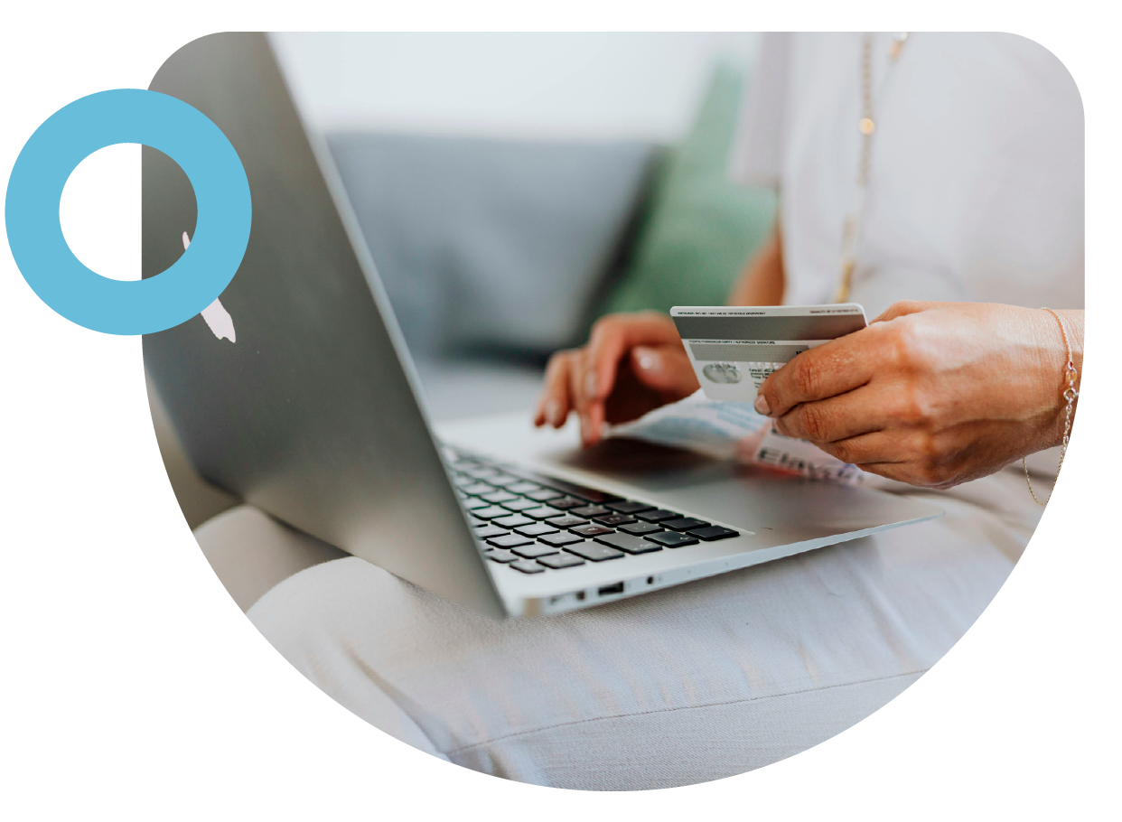 imagen de computador con una persona sosteniendo una tarjeta de crédito frente a el